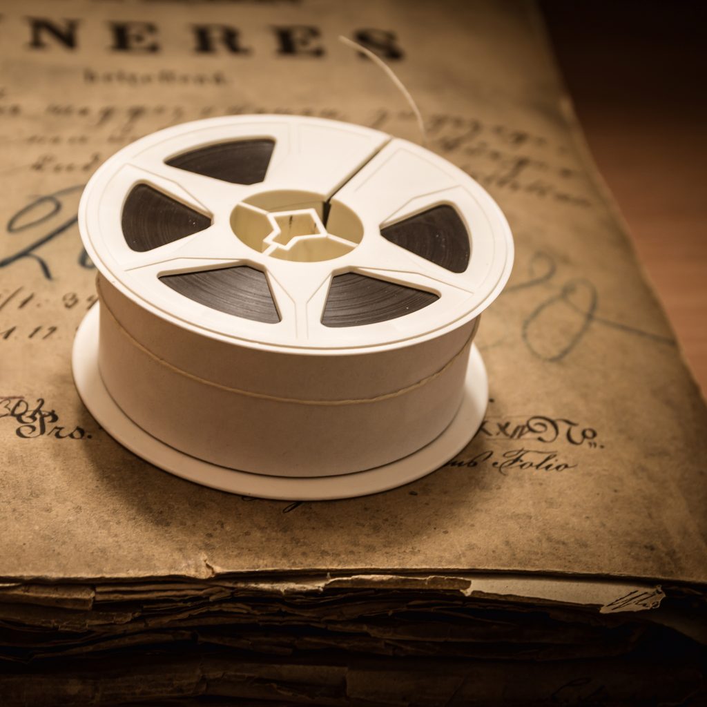 white 35mm microfilm reel on top of an old newspaper bound volume